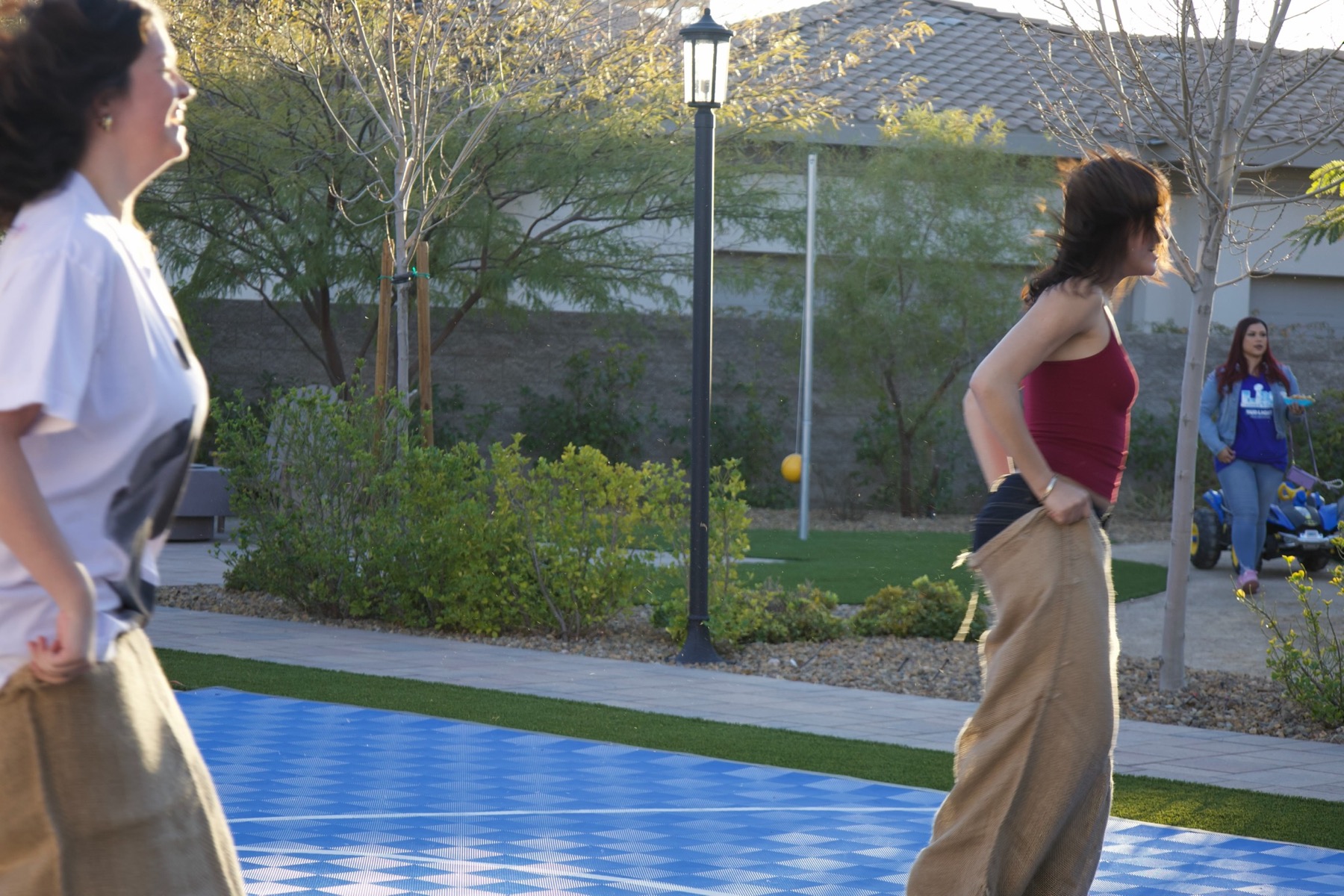 Guests racing in sacks at a bright outdoor Grazie Mille party