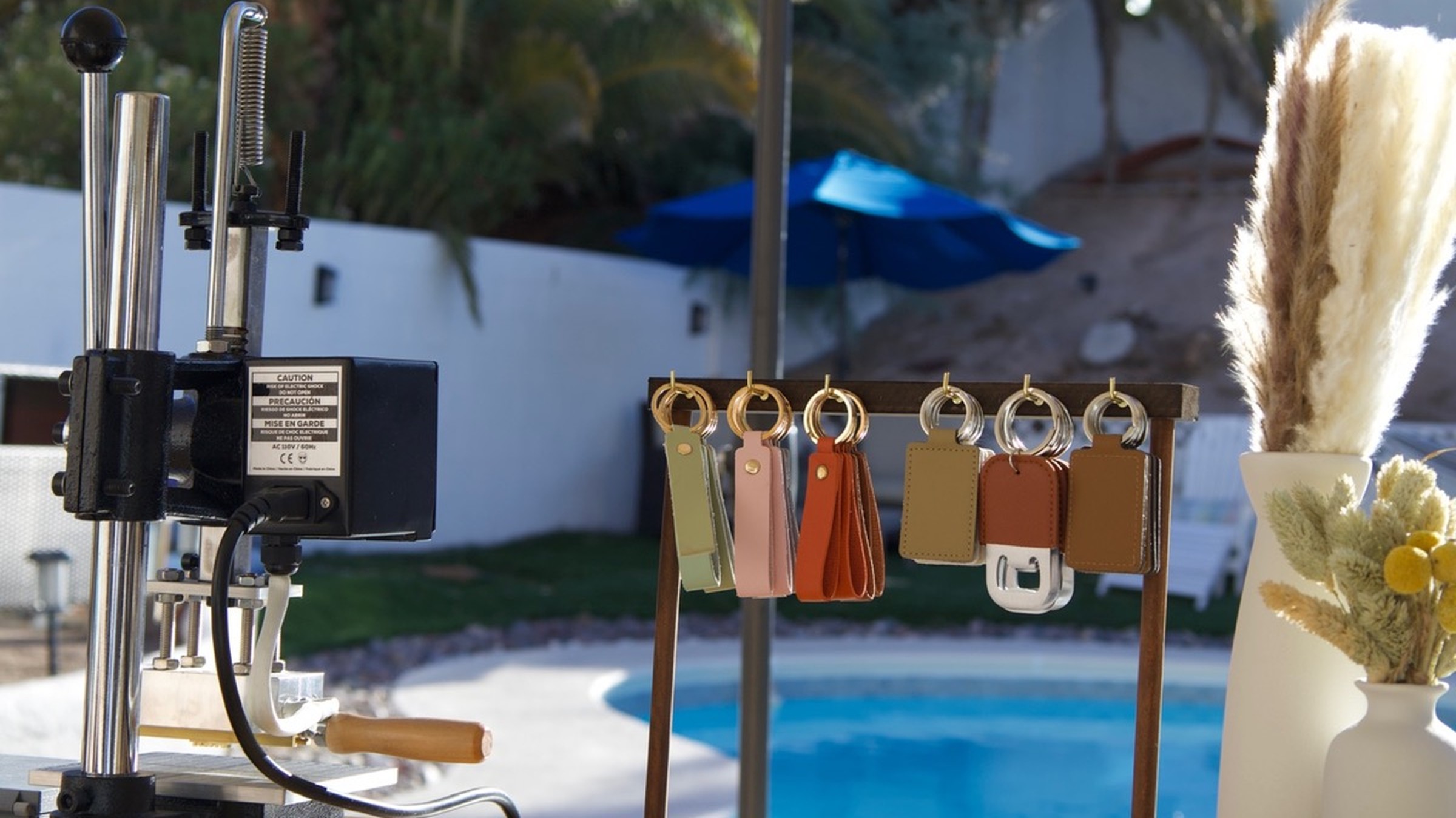 Imprint embossing press and colorful leather keychains set up poolside