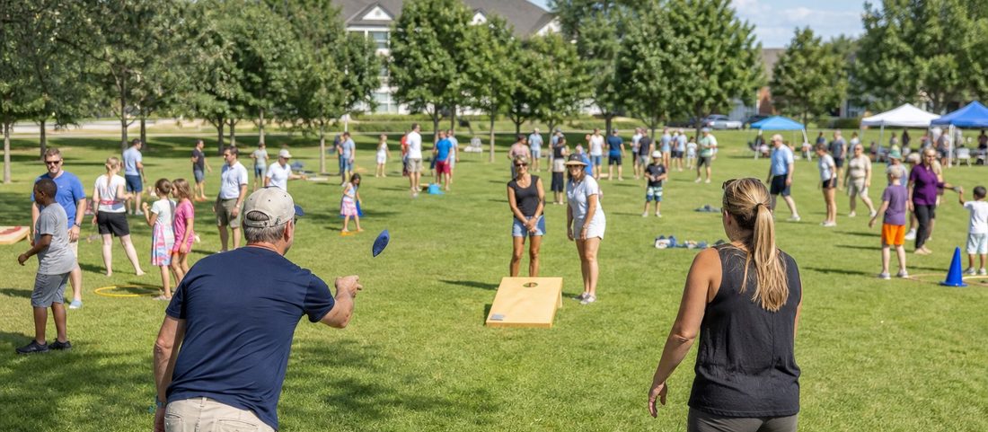 Neighbors and families playing lawn games together in an open community park