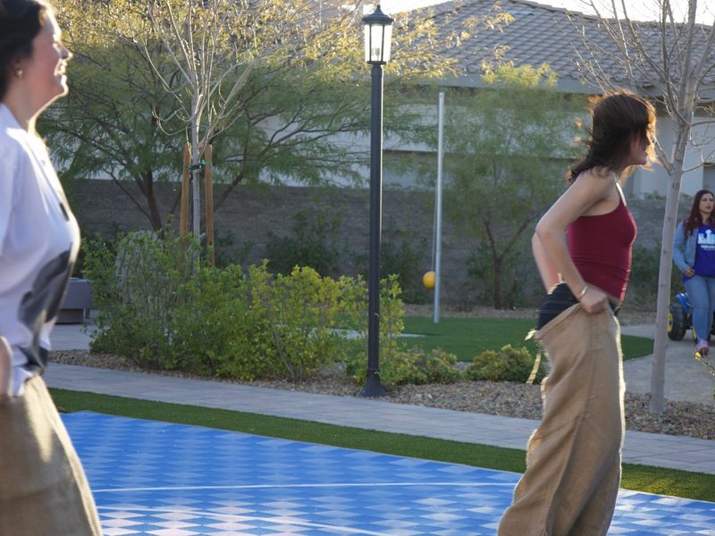 Guests racing in sacks at a bright outdoor Grazie Mille party